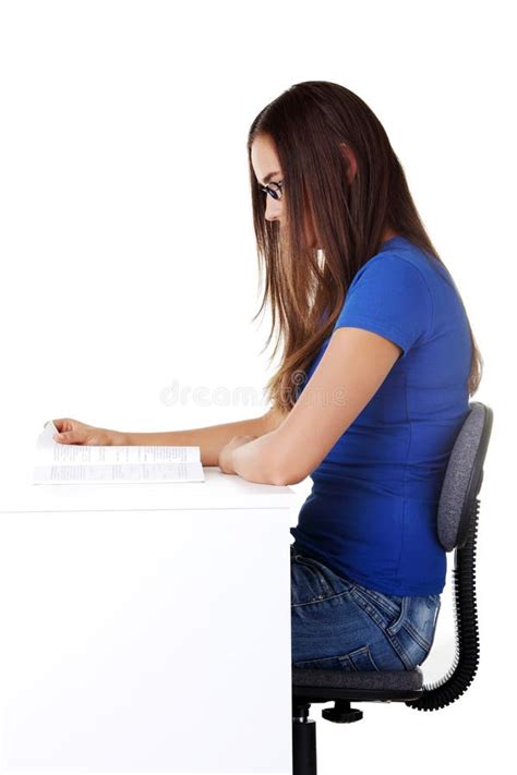 Young Beautiful Woman Sitting By The Desk And Reading Stock Image