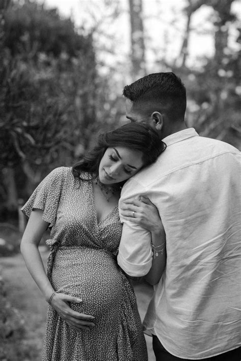 A Pregnant Couple Cuddles In The Woods For Their Black And White Photo Session