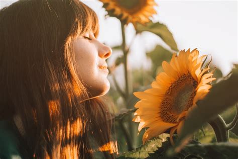 Smiling Woman In Sunlight Near Flower · Free Stock Photo
