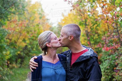 Couple Kissing While Walking Down A Park Path In Autumn Edmonton