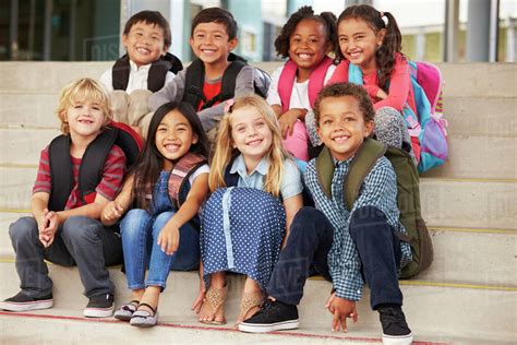 A Group Of Elementary School Kids Sitting On School Steps Stock Photo