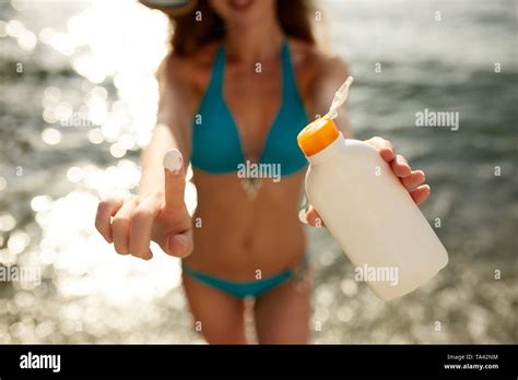 Closeup Of Smiling Caucasian Woman Showing Sunscreen Oil Bottle And Using Suntan Cream Smear On