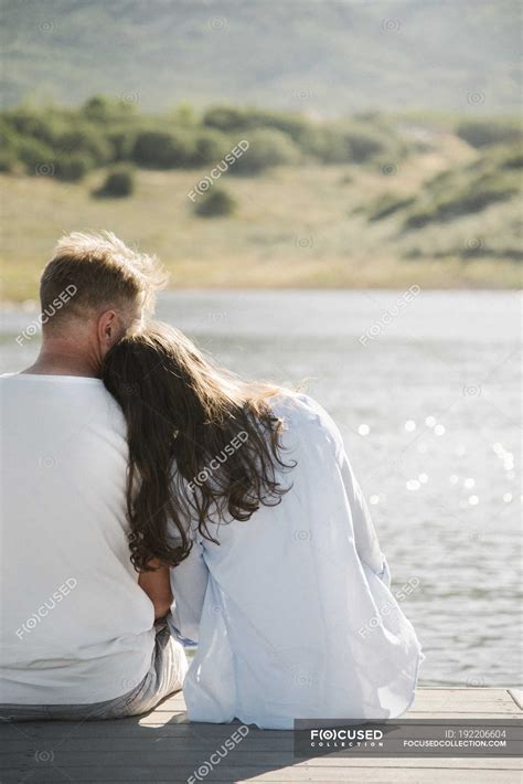 Woman Leaning On Male Shoulder While Sitting Side By Side On Jetty — Romantic Leaning On