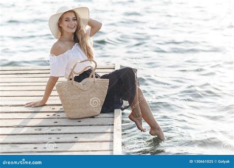 Portrait Of A Cute Girl Outdoors In Sitting On A Pier In The Spring