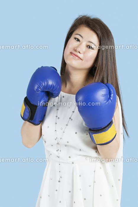Portrait Of A Beautiful Young Woman Wearing Boxing Gloves Over Blue