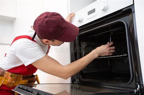 Handsome Young Repairman Fixing Oven With Screwdriver Stock Photo