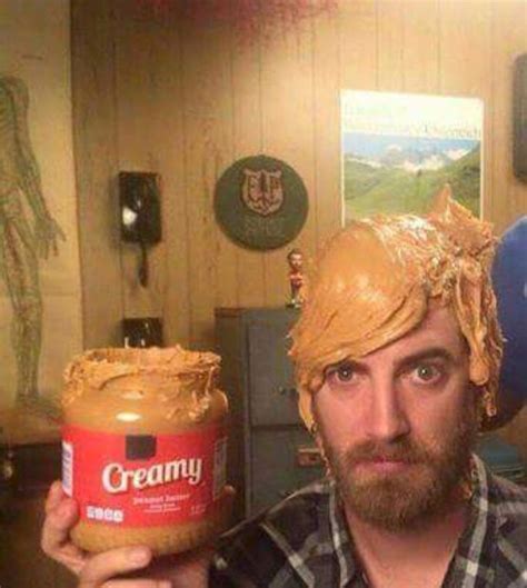 A Man Wearing A Wig Holding Up A Jar Of Peanut Butter In His Hand And Looking At The Camera