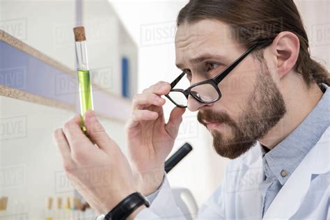 Young Male Scientist Looking At Chemical Sample In Test Tube Stock