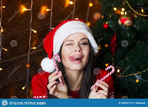 funny girl in santa hat with red lips and lollipop candy in her hand on christmas background