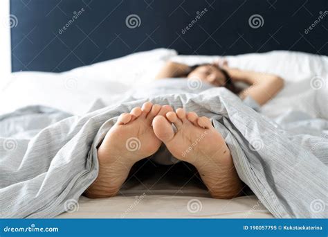 Feet Of Man Sleeping In Comfortable Bed Stretch After Wake Up In The