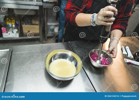 Unrecognizable Female Pastry Chef Prepares A Pink Icing For A Cake Whips It With A Blender In A