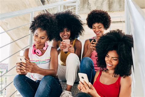 Afro Women Friends Hanging Out In The City Using Their Cellphones By Stocksy Contributor