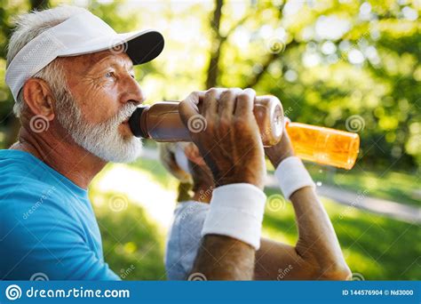 Hydrating Sporty Senior Person Drinking Water In A Park Stock Photo