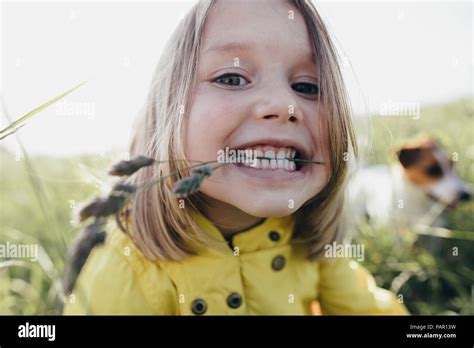 Portrait Of Little Girl On A Meadow Holding Blade Of Grass With Her