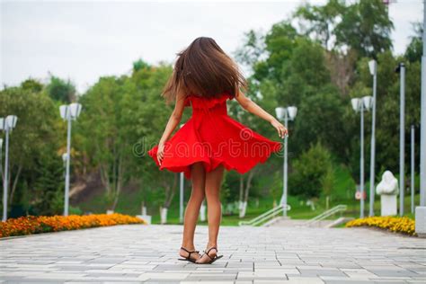 Young Beautiful Woman In Red Dress Walking On The Summer Street Stock