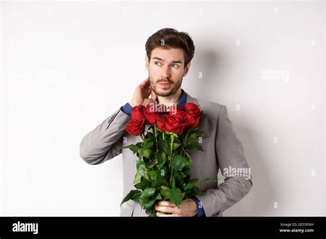 Pensive Young Man In Suit Holding Bouquet Of Flowers Waiting For Date