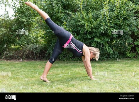 Side View Of Athletic Senior Blond Woman In Forward Bend Pose With