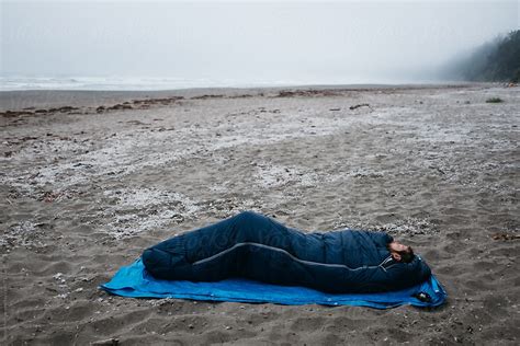 Young Male Sleeping Alone On Beach In Sleeping Bag By Jesse Morrow