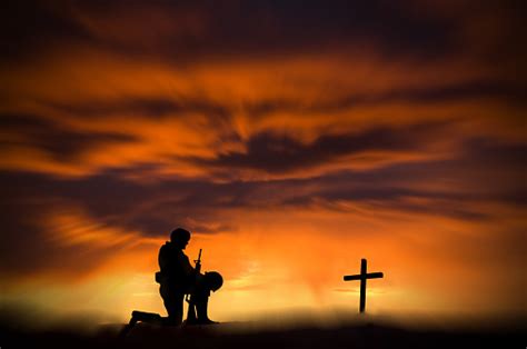 Soldier Kneeling In Front Of A Grave And Cross Zoom Stock Photo