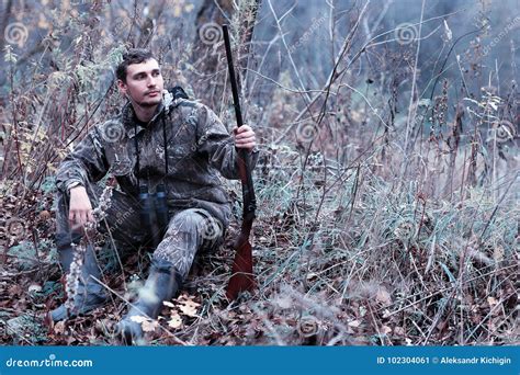 A Man In Camouflage And With A Hunting Rifle In A Forest On A Sp Stock