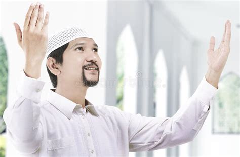 Asian Muslim Man Standing While Raised Hands And Praying Stock Image