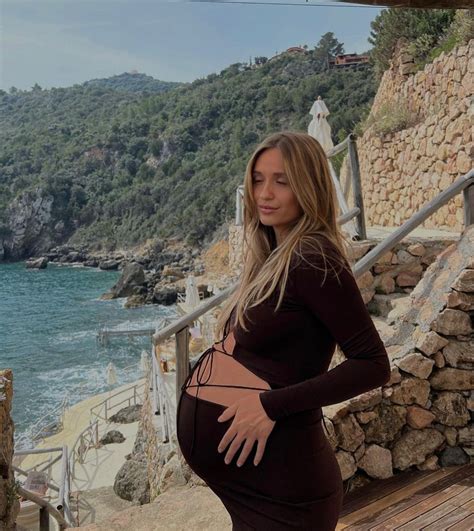 A Pregnant Woman Is Standing On The Steps By The Water And Looking At