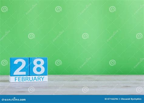 February 28th Cube Calendar For February 28 On Wooden Desk With Green