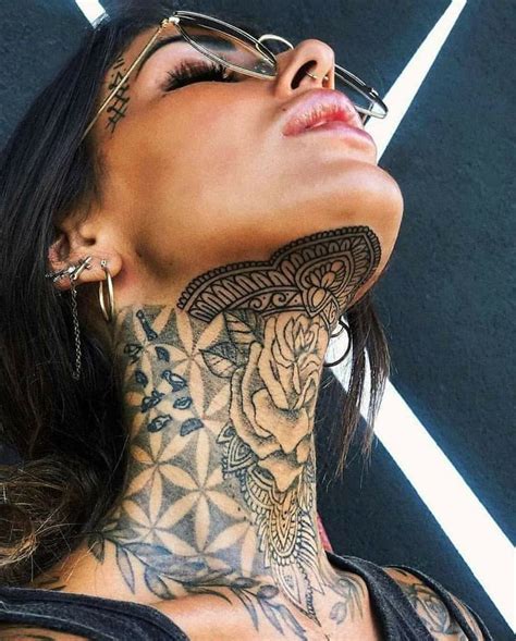 A Woman With Tattoos On Her Neck Is Looking Up At The Sky While Wearing Glasses