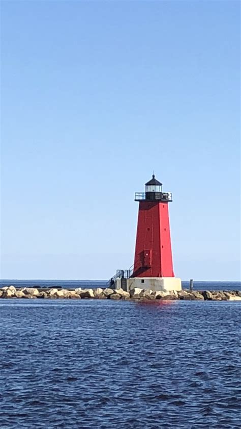 A Red And White Light House Sitting On Top Of A Body Of Water