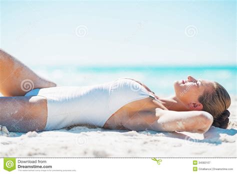 jovem mulher feliz no roupa de banho que bronzea se na praia imagem de stock imagem de