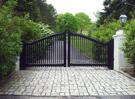 A Transitional Style Driveway Gate Features The Arch And Pickets Of A