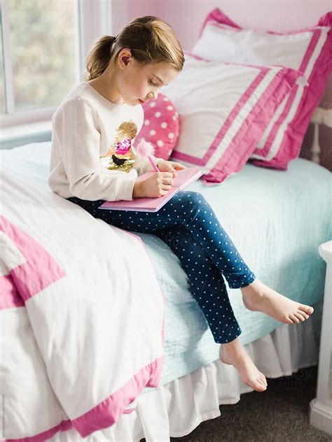 Young Girl Sitting On Bed Writing In Her Diary Del Colaborador De