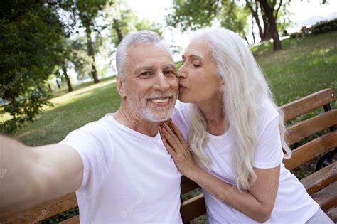 premium photo gladsome man taking selfies with his wife in a park and getting a kiss