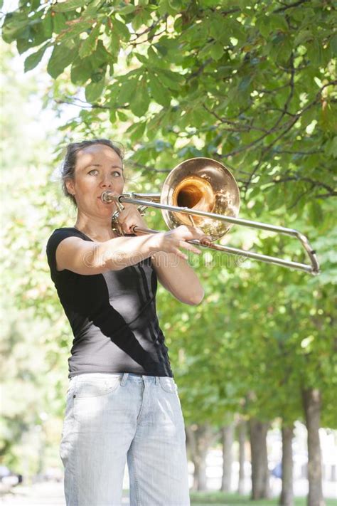 girl learning to play trombone girl plays standing on the alley of a city park stock image