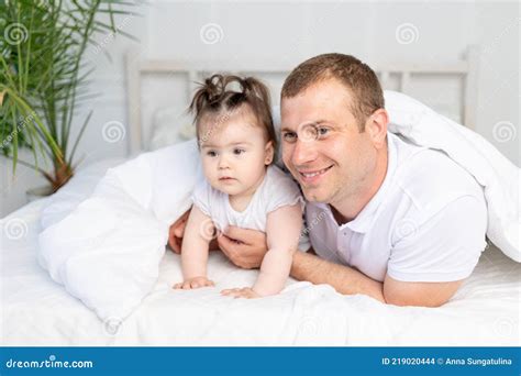 Padre E Hija Bebé En La Cama Bajo La Manta Sonriendo Y Abrazándose