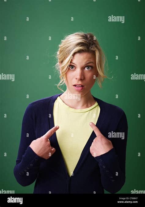 Young Woman Pointing At Herself Against Green Background And Looking At