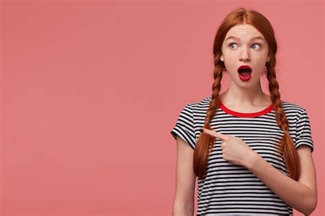 Шокированная взволнованная девочка подросток с двумя рыжими косами красная помада открытая
