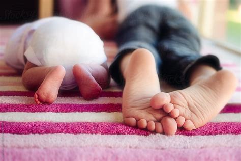 Close Up Of A Young Childs Feet Lying Next To His Newborn Sisters