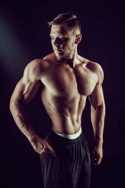 Bodybuilder Posant Fitness Homme Musclé Sur Mur Sombre Photo Premium