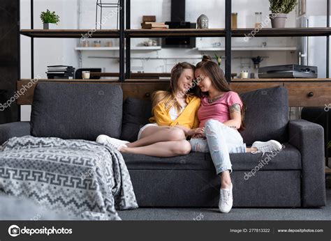 Two Smiling Lesbians Holding Hands While Sitting Sofa Living Room Stock