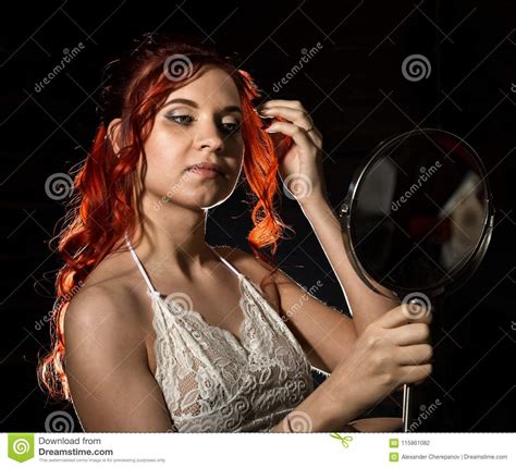 Young Redhead Woman Holding A Round Mirror At Home And Correcting Her