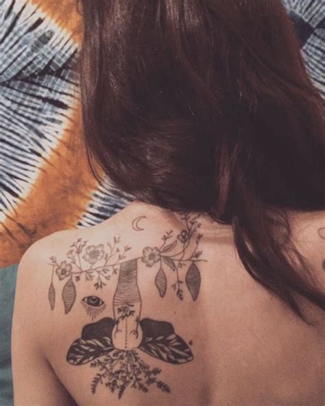 The Back Of A Womans Upper Half With Tattoos On Her Shoulder And Chest