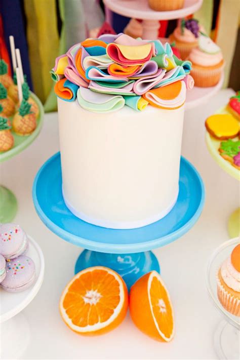 There Is A White Cake With Orange Slices On The Plate Next To Cupcakes