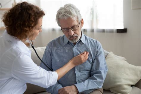 Caring Female Doctor Listen To Heart Of Mature Patient Stock Image