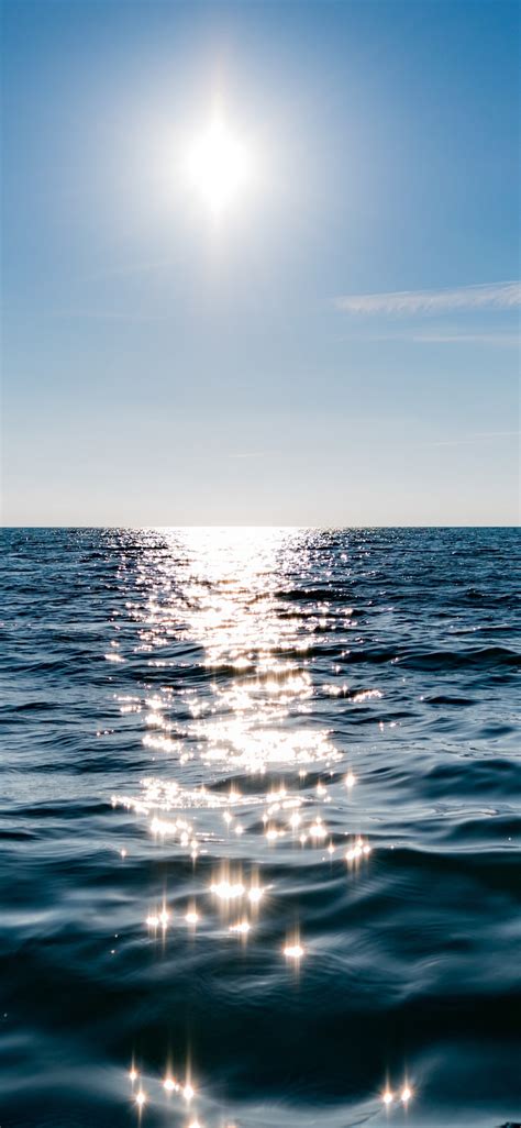 Download Wallpaper Sun On Blue Sky Is Reflected On Water 1125x2436