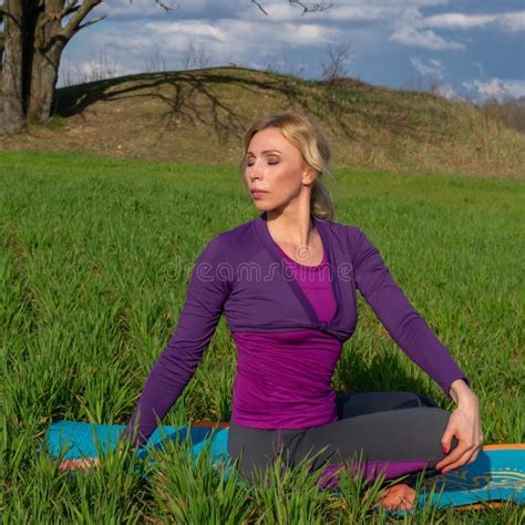A Middle Aged Blonde Woman Practices Yoga In Nature Healthy Lifestyle