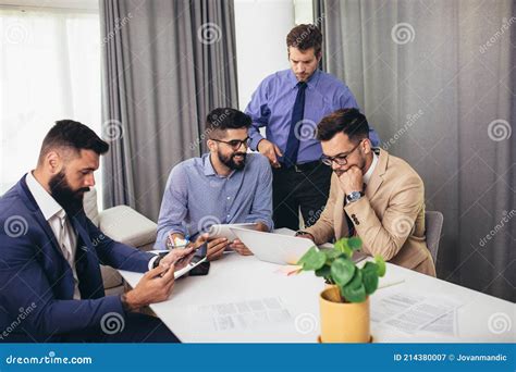 Colleagues At Meeting In Boardroom Sitting At Table Together Sharing