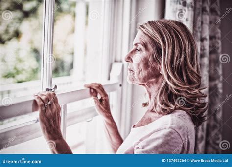 Thoughtful Senior Woman Looking Out From The Window Stock Photo Image