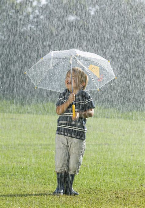Boy Standing With Umbrella In Rain Stock Photo