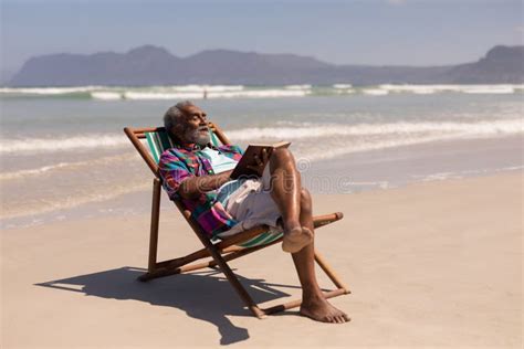 Senior Man Relaxing On Sun Lounger And Reading A Book On Beach Stock Image Image Of Lifestyle